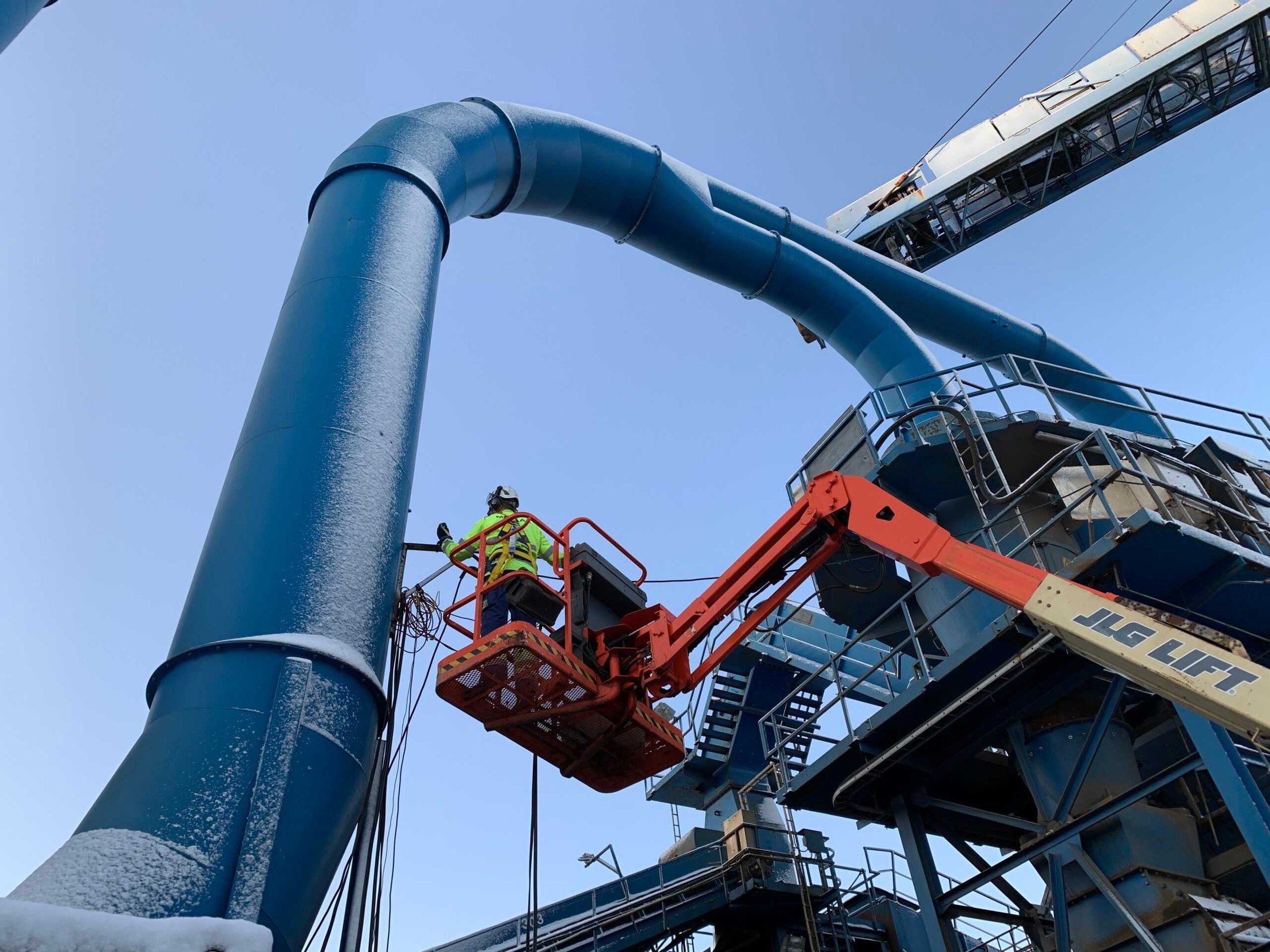 METLAB measurement engineer in a boom lift beside a blue flue gas duct
