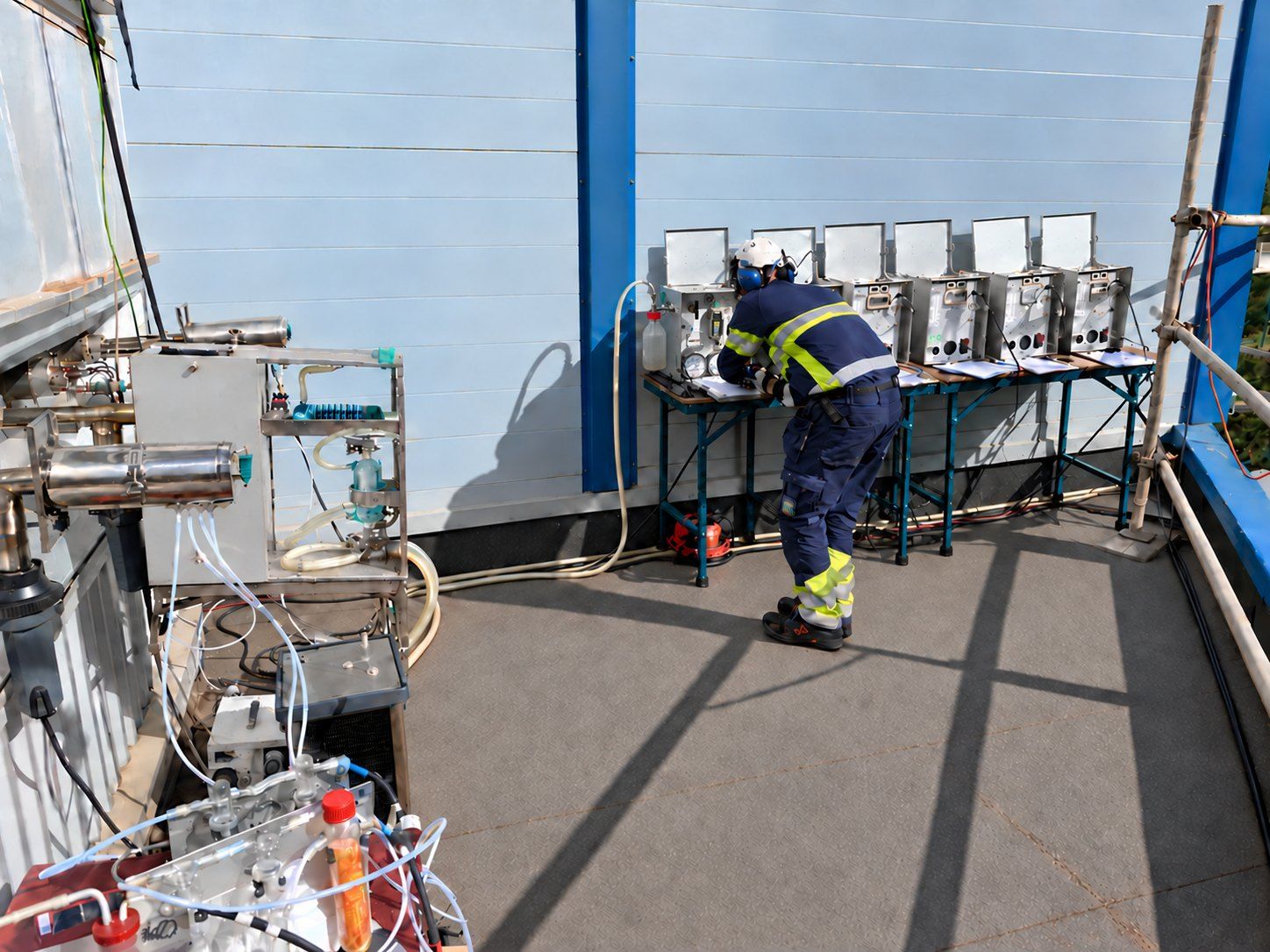 Measurement engineer at sampling equipment on a sunlit platform