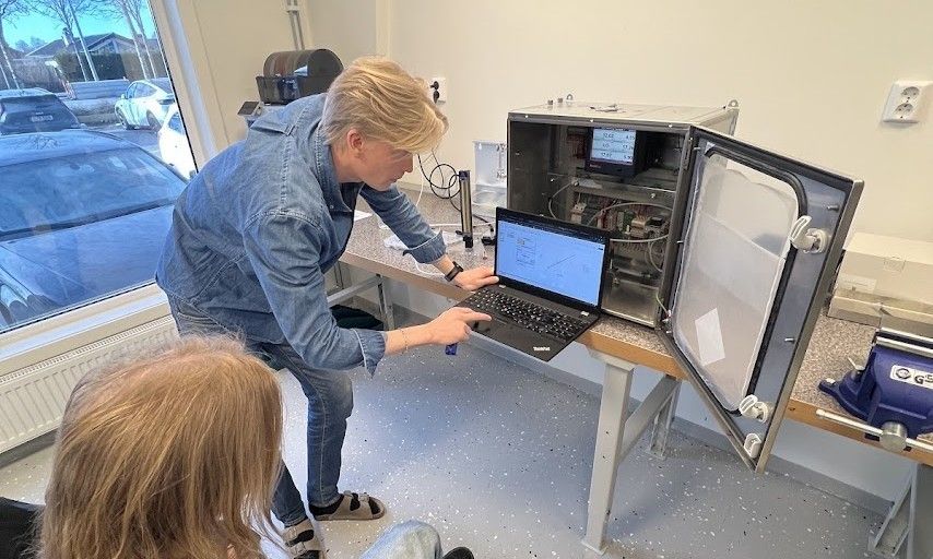 Två medarbetare testar en provtagare vid en bänk i laboratoriet