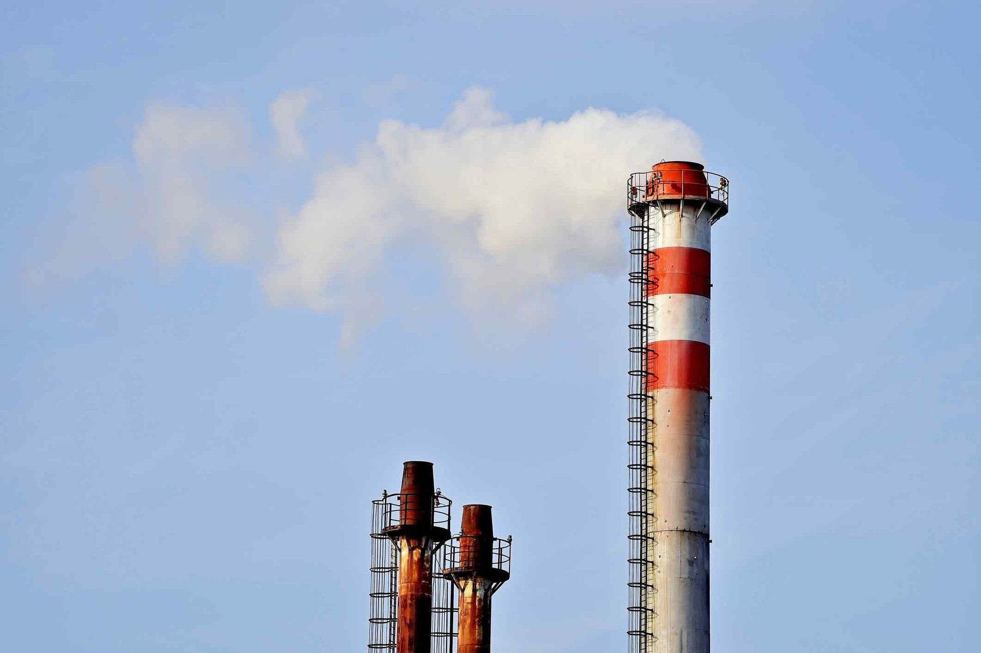 Two stacks with a flue gas plume against a blue sky